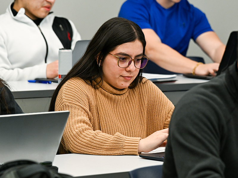 students working on laptops in a classroom on campus